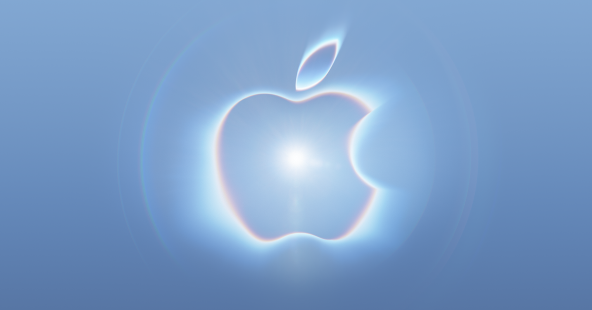 A large, softly glowing Apple logo centered on a pale blue background, surrounded by hazy light, lens flare, and faint circular halos.